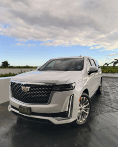 A white Cadillac SUV is parked on a driveway under a partly cloudy sky, special for cancun luxury transportation